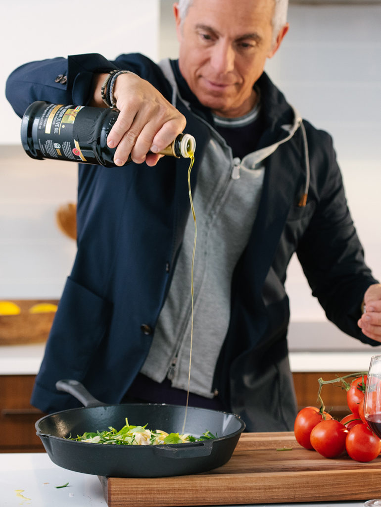 A photo of Geoffrey Zakarian pouring olive oil into a cast iron skillet