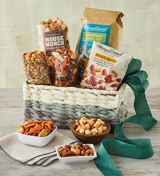 A photo of gifts for men with a basket full of mixed nuts, caramel corn and other snacks with the same ingredients in three bowls in front of the basket.