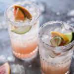 A photo of a paloma cocktail recipe with two glasses full of ice, juice, and lime wedges