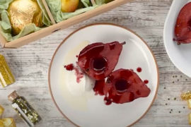 A photo of red wine poached pears on a plate surrounded by ingredients