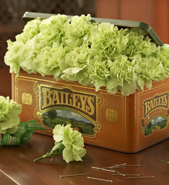 A photo of St. Patrick's Day celebrations with a Bailey's tin overflowing with green flowers.