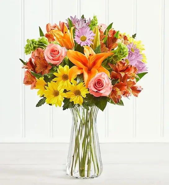 A photo of birthday gifts for sister with a bouquet of flowers in a clear vase.