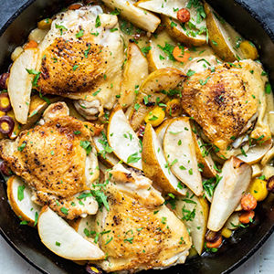 A photo of chicken recipes with a skillet full of chicken thighs and pears
