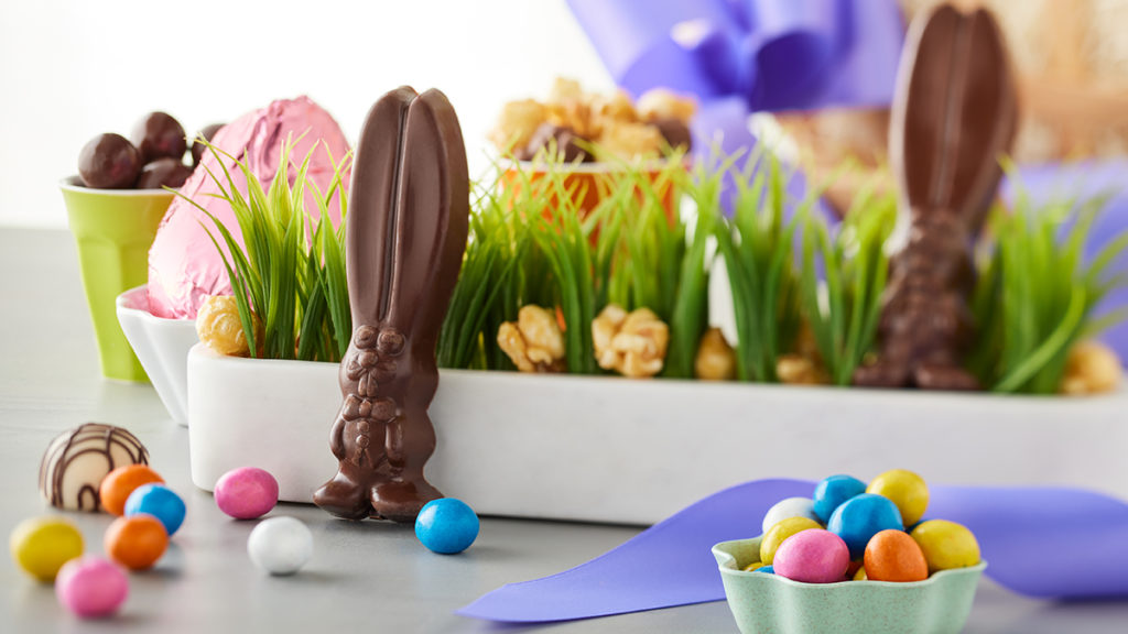 A photo of Easter facts with an Easter chocolate bunny and other candies nestled into fake grass