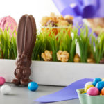 A photo of Easter facts with an Easter chocolate bunny and other candies nestled into fake grass