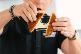 A photo of grilled cheese being pulled apart by Geoffrey Zakarian
