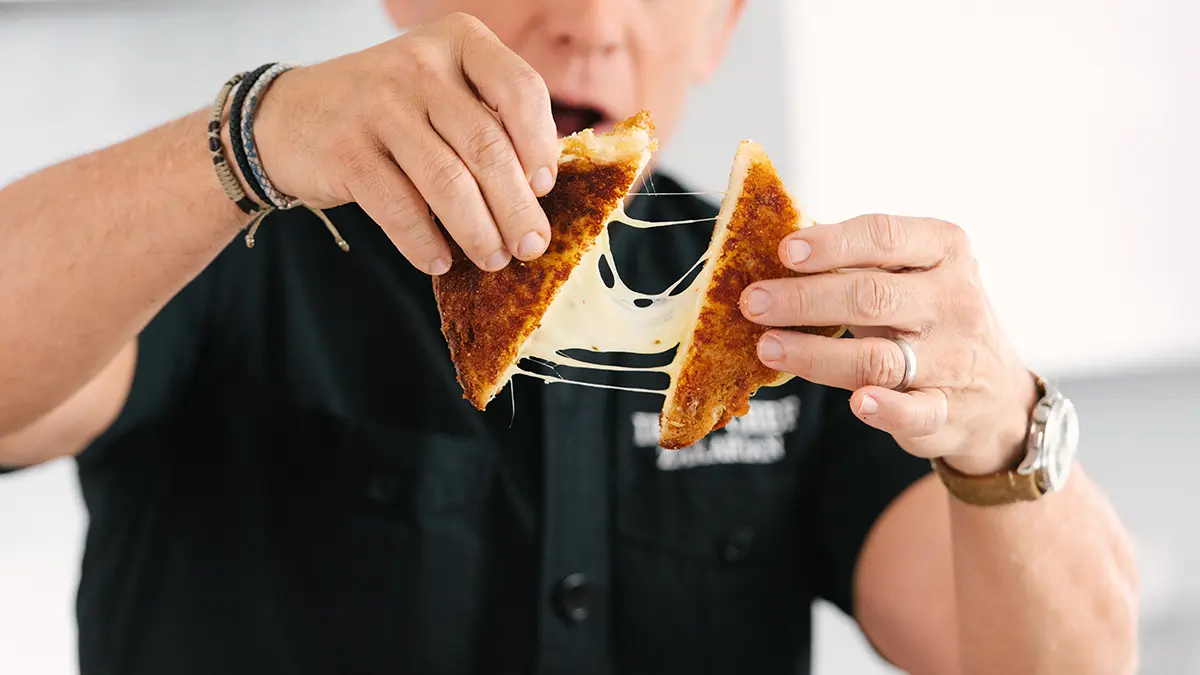 A photo of grilled cheese being pulled apart by Geoffrey Zakarian