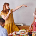 A photo of International Women's Day with two women dancing and singing at a breakfast table.