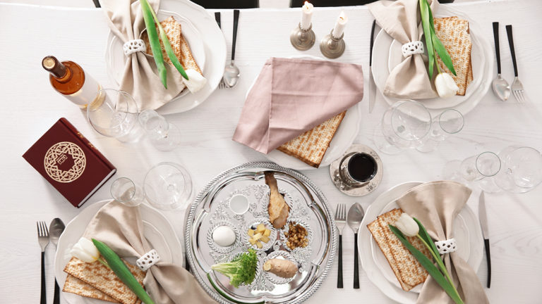 A photo of Passover wine with a table spread for the Seder with wine, flowers and food.