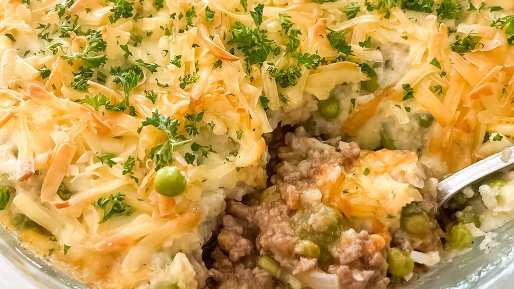 A photo of shepherd's pie with a spoon cutting into the pie