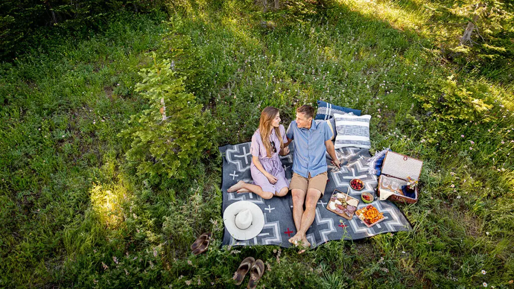 A photo of spring equinox activities with a couple having a picnic in a green field