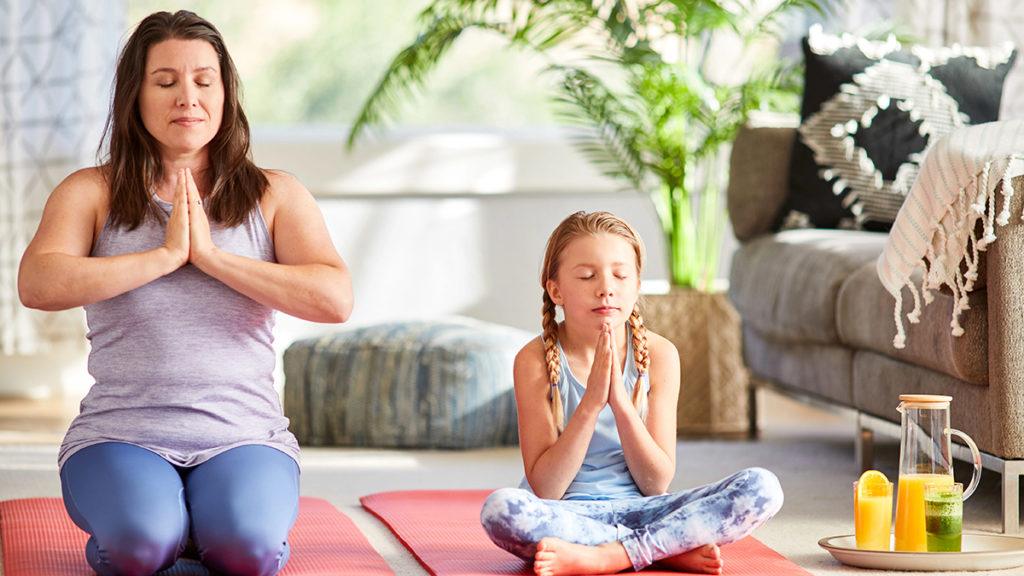 A photo of spring self-care ideas with a woman and a young girl doing yoga next to a each other.