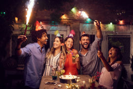 A photo of surprise birthday party with a group of people celebrating outside with roman candles