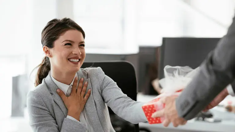 A photo of Administrative Professionals Day with a woman accepting a gift and smiling