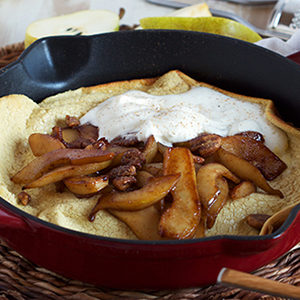 A photo of breakfast recipes with a Dutch baby in a cast-iron pan and sliced pears on top