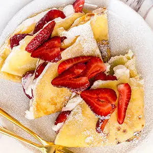 A photo of breakfast recipes with strawberry crepes on a plate