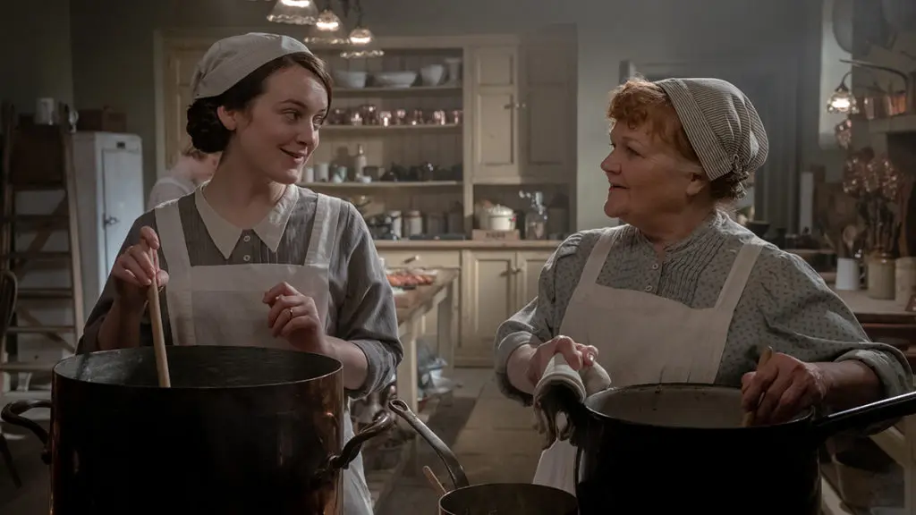 A photo of Downton Abbey party with two women in a kitchen cooking