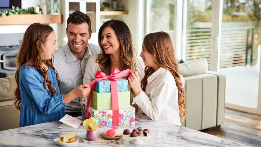 A photo of gifts for hard to buy for with a family sitting around a large stack of presents