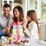 A photo of gifts for hard to buy for with a family sitting around a large stack of presents
