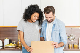 A photo of gifts for new homeowners with a man and woman opening a box