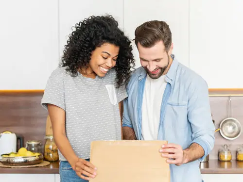 A photo of gifts for new homeowners with a man and woman opening a box