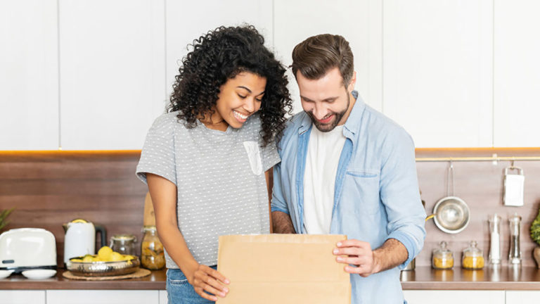 A photo of gifts for new homeowners with a man and woman opening a box