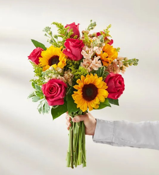 A photo of gifts for new moms with a hand holding a bouquet of flowers