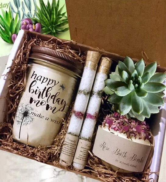 A photo of gifts for new moms with a box of candles, succulents, and bath salts