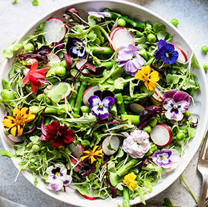 A photo of may recipes with a bowl of spring salad with edible flowers