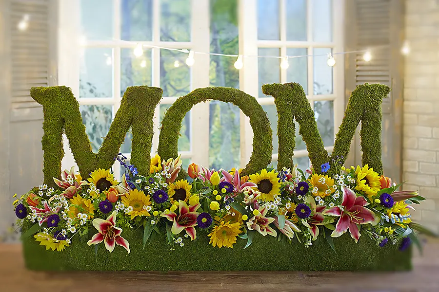 A photo of mother's day wine tasting with a hedge that spells mom