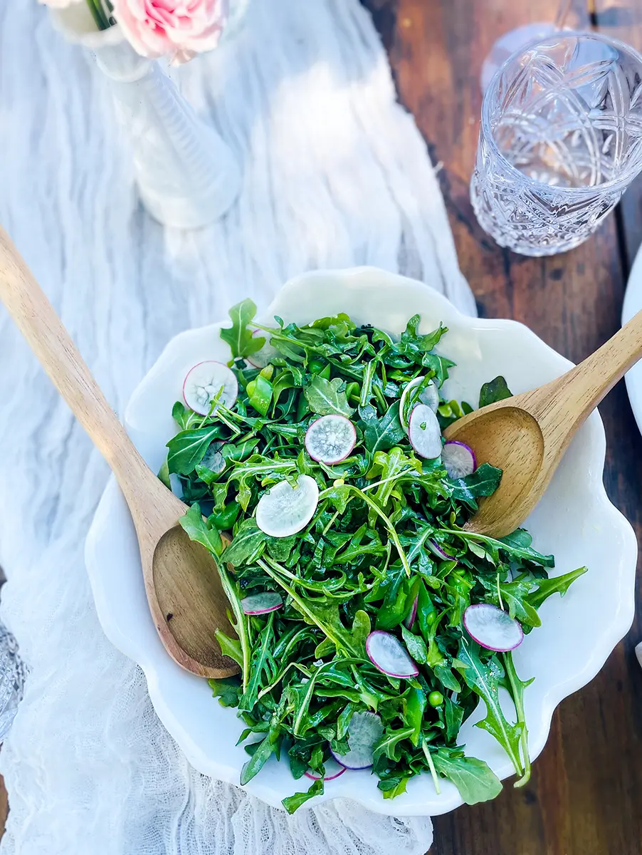 A photo of mother's day brunch recipes with a closeup of a salad in a bowl on a table.