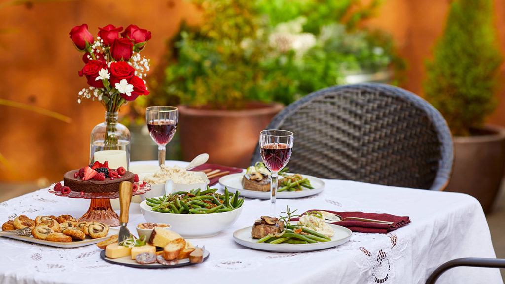 A photo of Mother's Day dinner ideas with a table laid for two people with a spread of food on top.