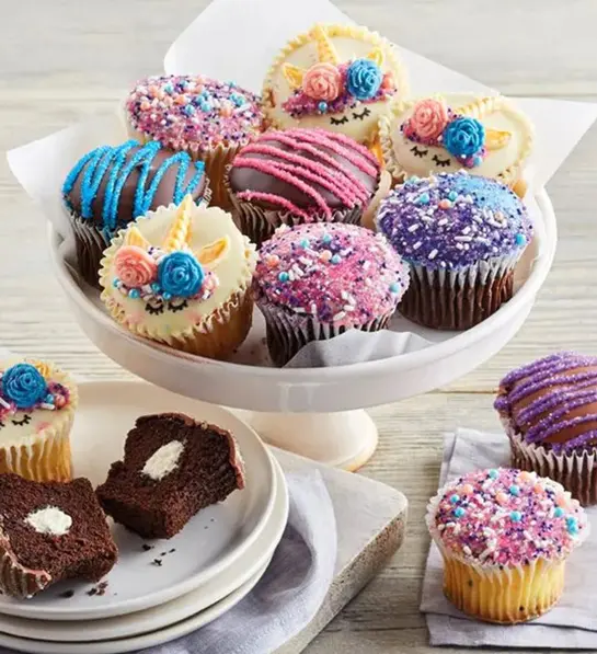 A photo of picnic with a plate of unicorn cupcakes