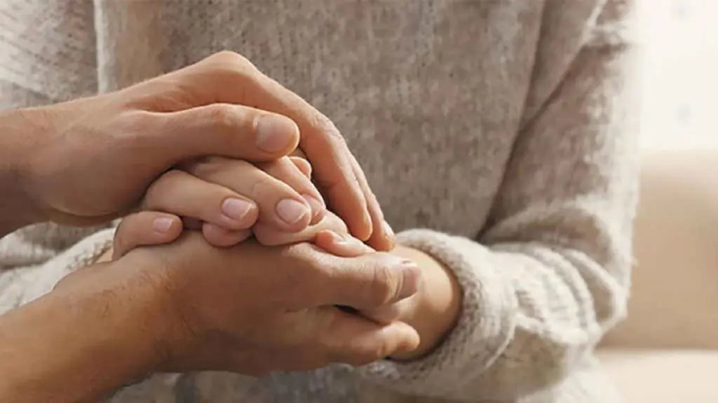 A photo of sympathy with two pairs of hands holding each other.