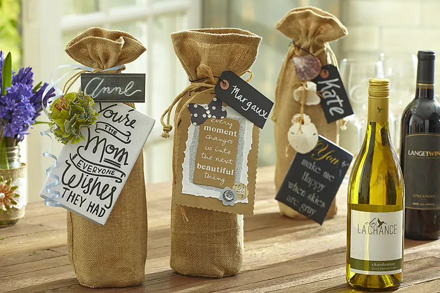 A photo of mother's day wine tasting with several bottles of wine in burlap totes with name tags