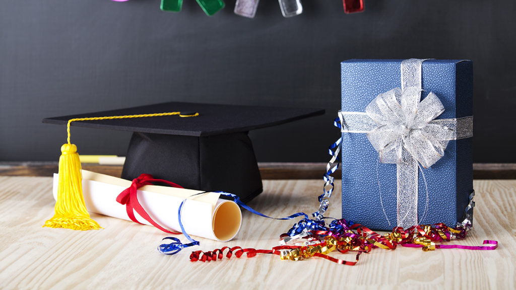 A photo of best graduation gift ideas with a present next to a graduation cap