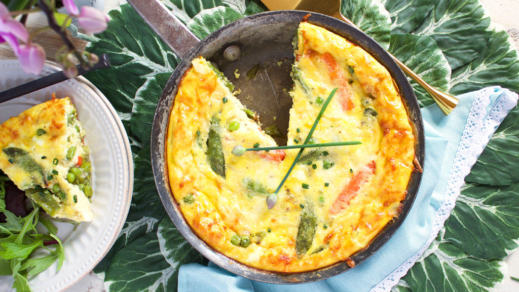 A photo of breakfast ideas with a frittata in a pan next to a plate