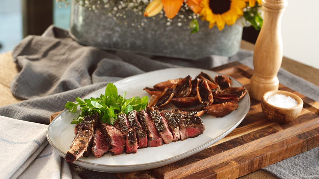 A photo of indoor grilling with a plate of steak and roasted shallots