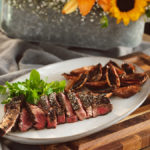 A photo of indoor grilling with a plate of steak and roasted shallots