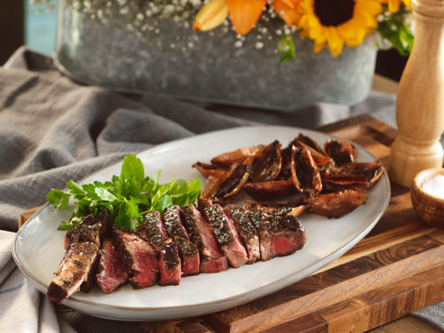 A photo of indoor grilling with a plate of steak and roasted shallots