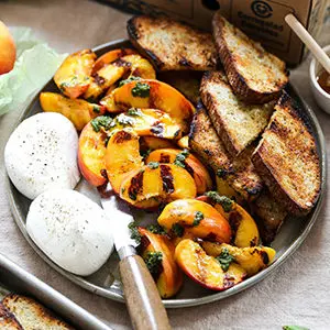 A photo of june recipes with a plate of grilled peaches, burrata and toasted bread