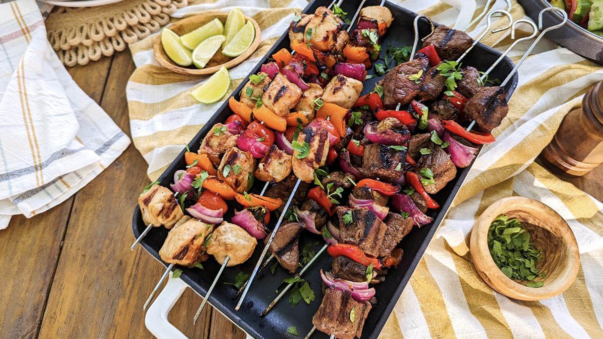 A photo of kebabs with a tray of steak and chicken kebabs on a table