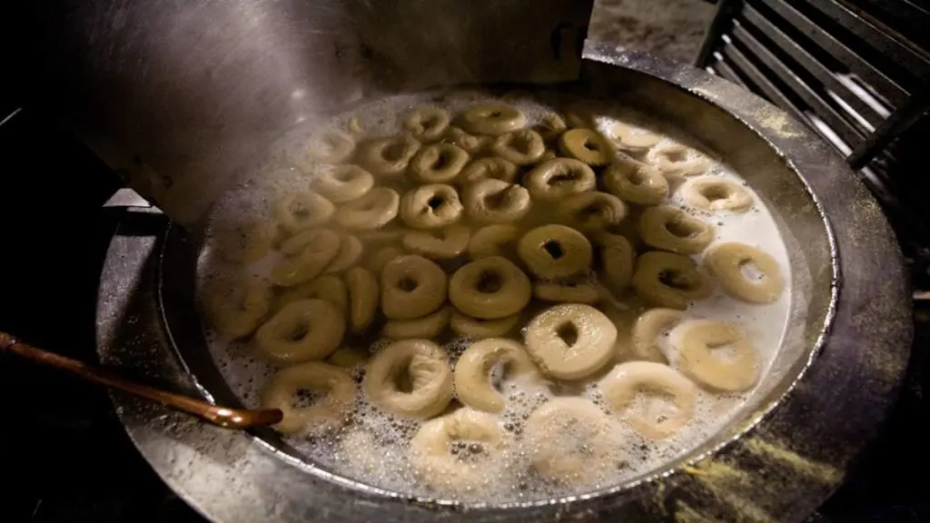 A photo of origin of the bagel with a batch of bagels boiling in a large pot of water