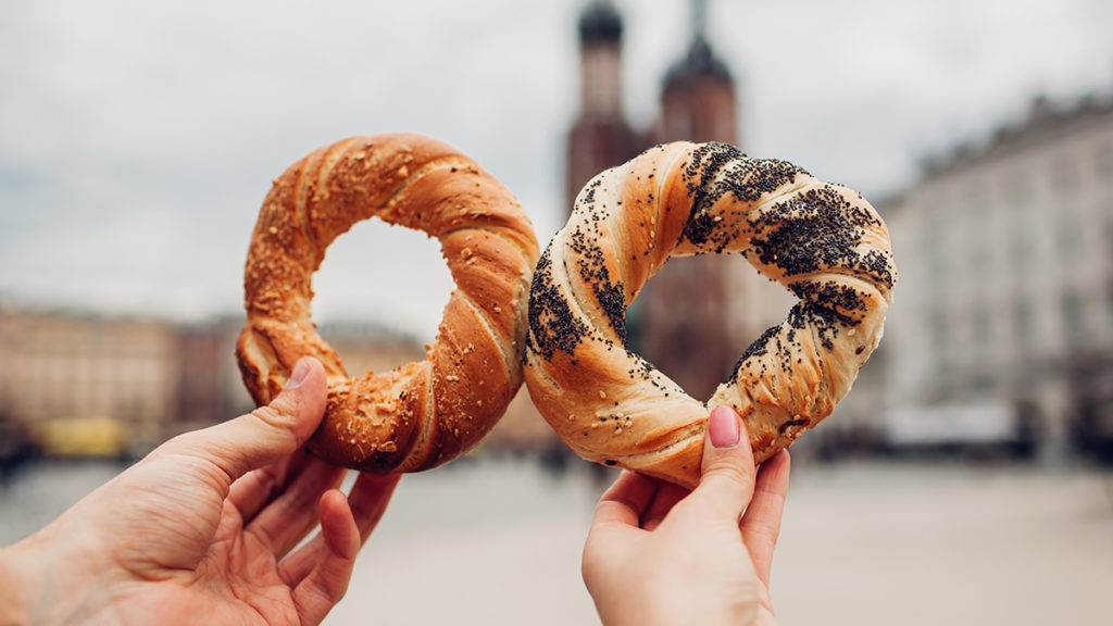 A photo of origin of the bagel with two hands holding up obwarzanek or Polish bagels