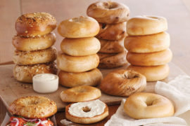 A photo of origin of the bagel with a stack of bagels on a wooden table