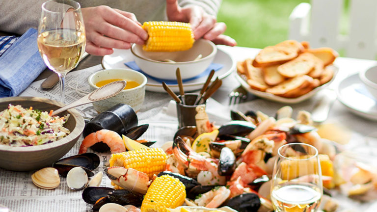 A photo of wine with fish with a table full of seafood and glasses of wine