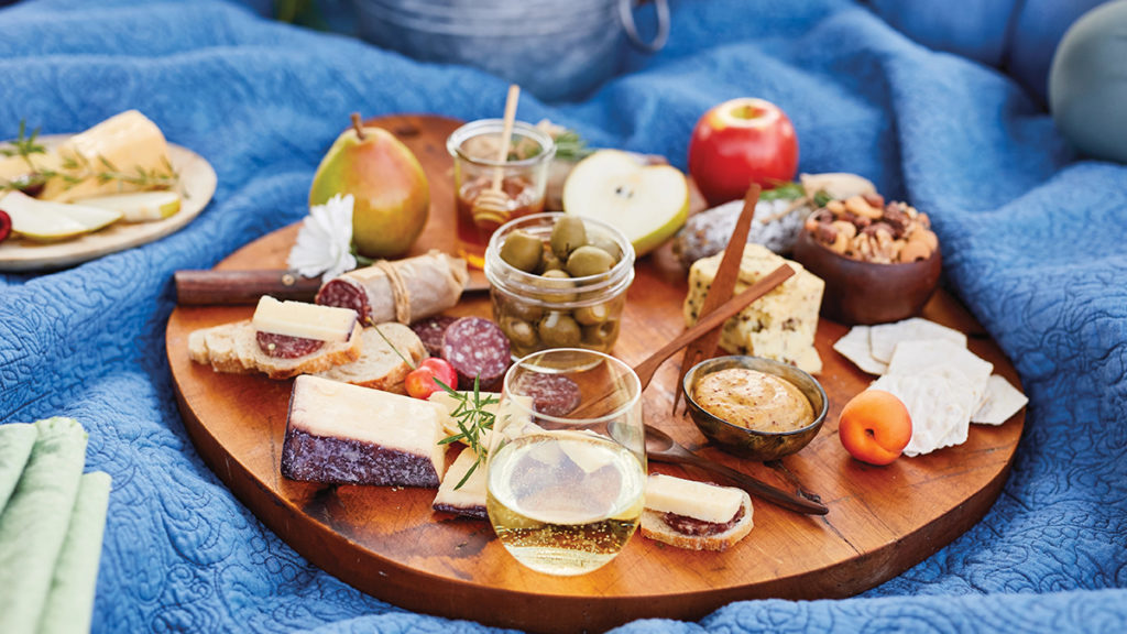 A photo of zodiac sign food with a charcuterie board on a blue picnic blanket