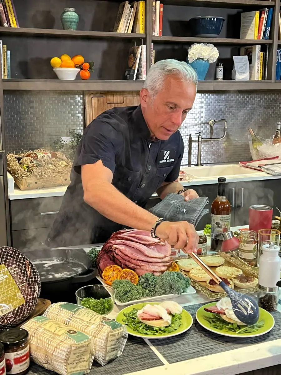 Photo of summer entertaining recipes with Geoffrey Zakarian making eggs Benedict in a kitchen.