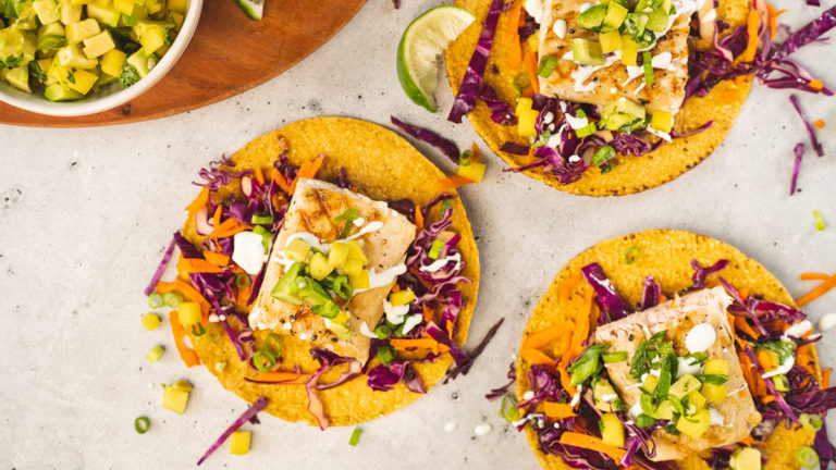 Photo of grilled fish tostadas next to a bowl of pineapple salsa