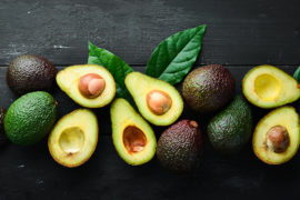 Photo of how to ripen an avocado with several avocados whole and cut in half on a table